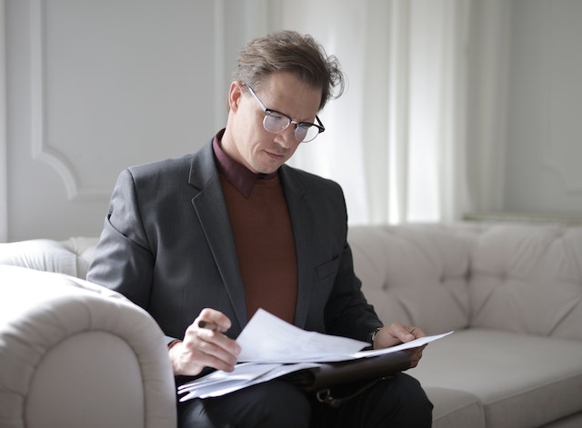 landlord sitting on a light gray couch looking over lease documents